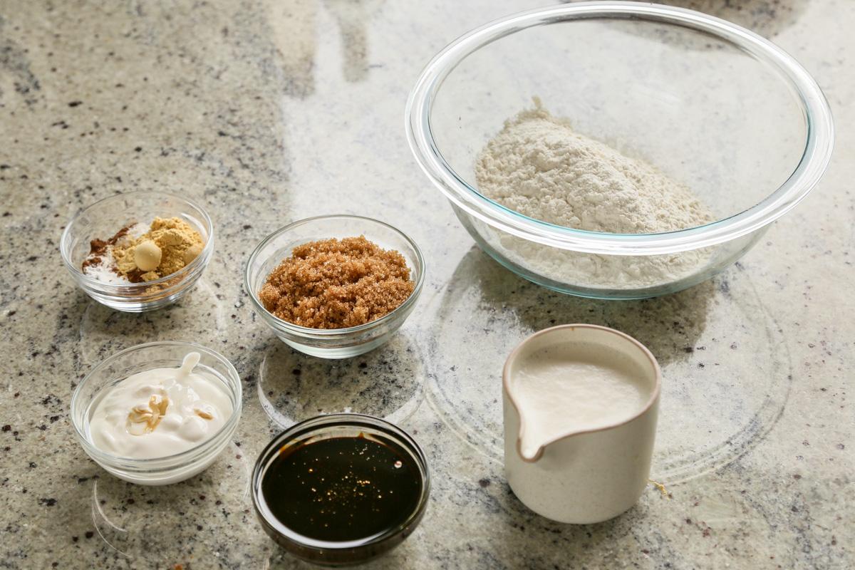 flour, ginger, brown sugar, and other cake ingredients in bowls on a white table