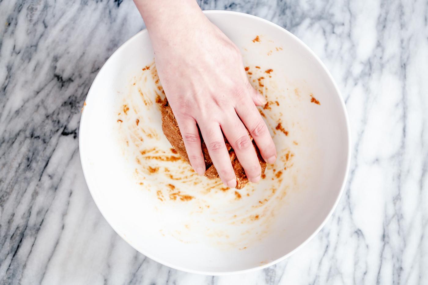 vegan gingerbread cookie dough being needed by hand in a small bowl