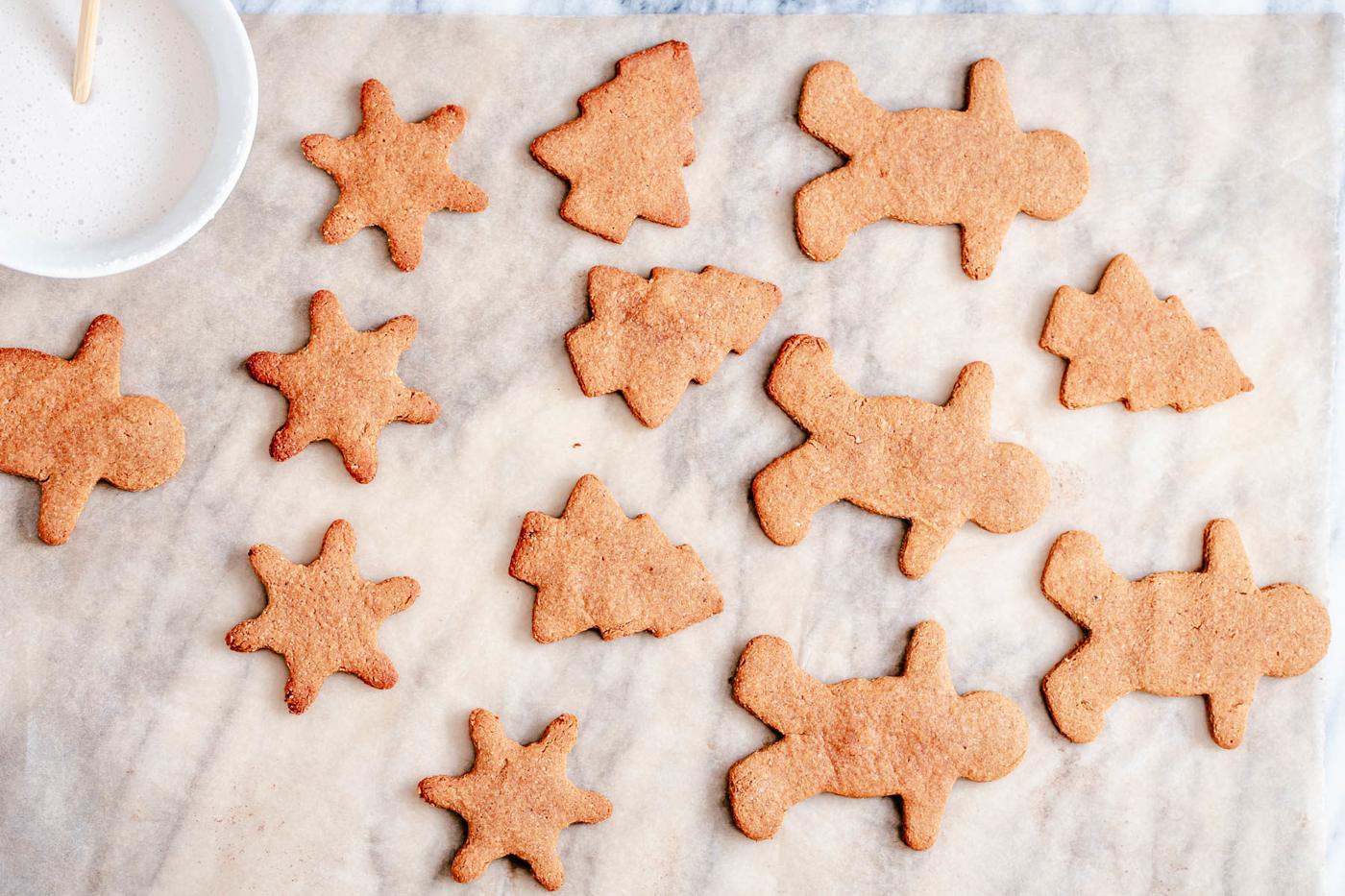 vegan gingerbread cookies cooling on a countertop with small bowl of icing