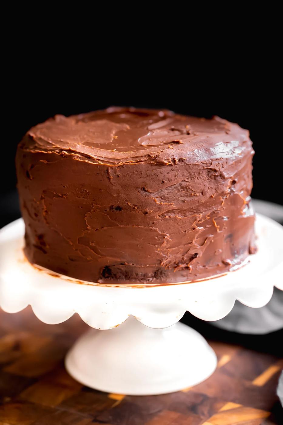 vegan chocolate layer cake frosted with vegan ganache on a cake stand