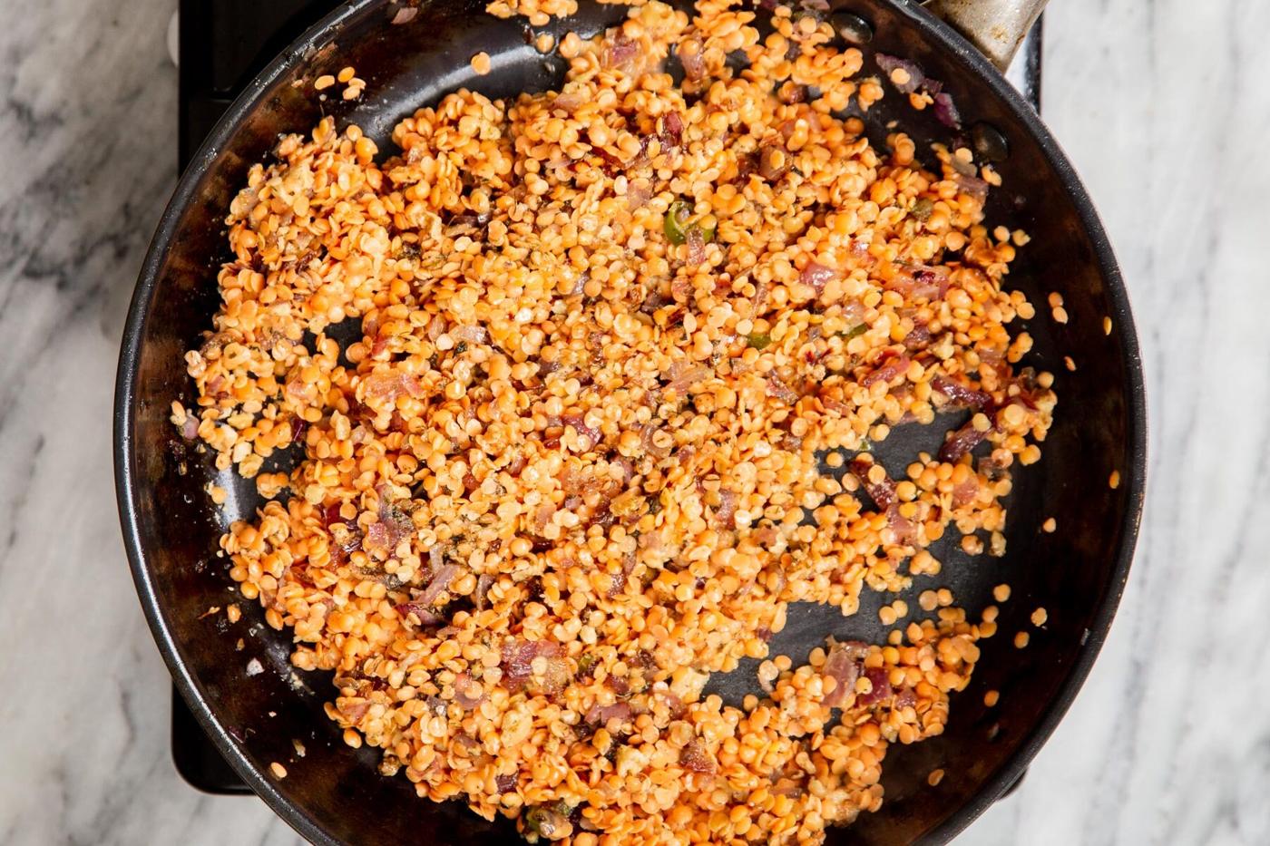 red lentils and sauteed onions in a black frying pan