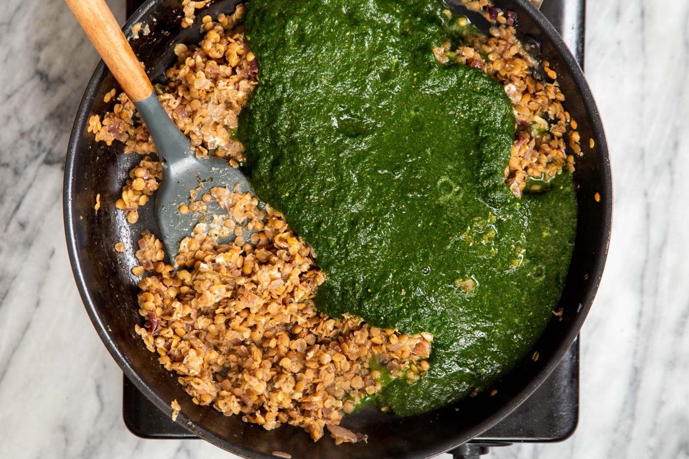 green herb sauce being added to skillet with lentils