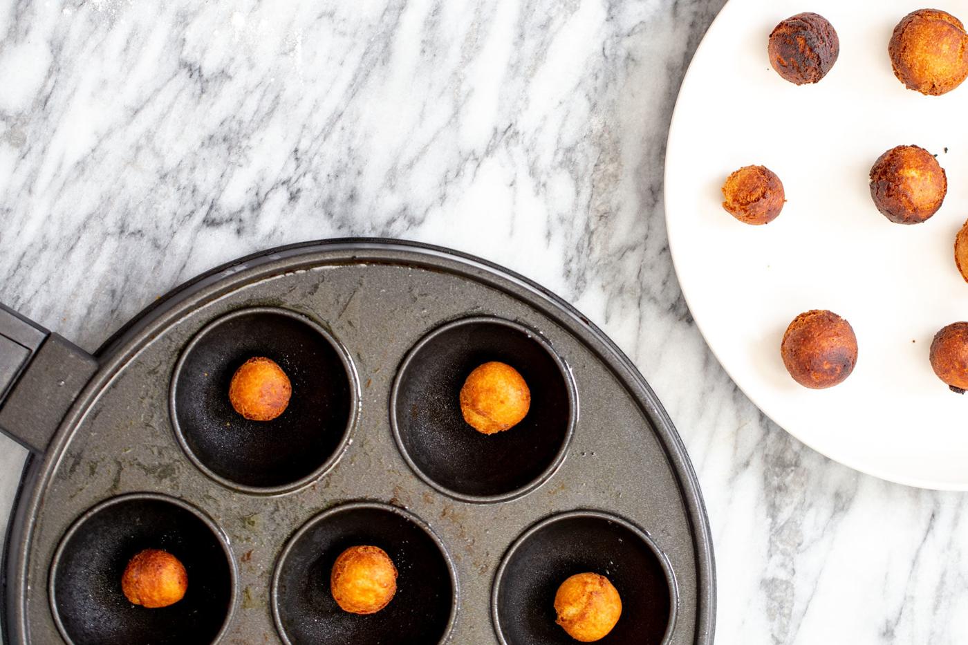 homemade vegan gulab jamun donuts being made in an appe pan