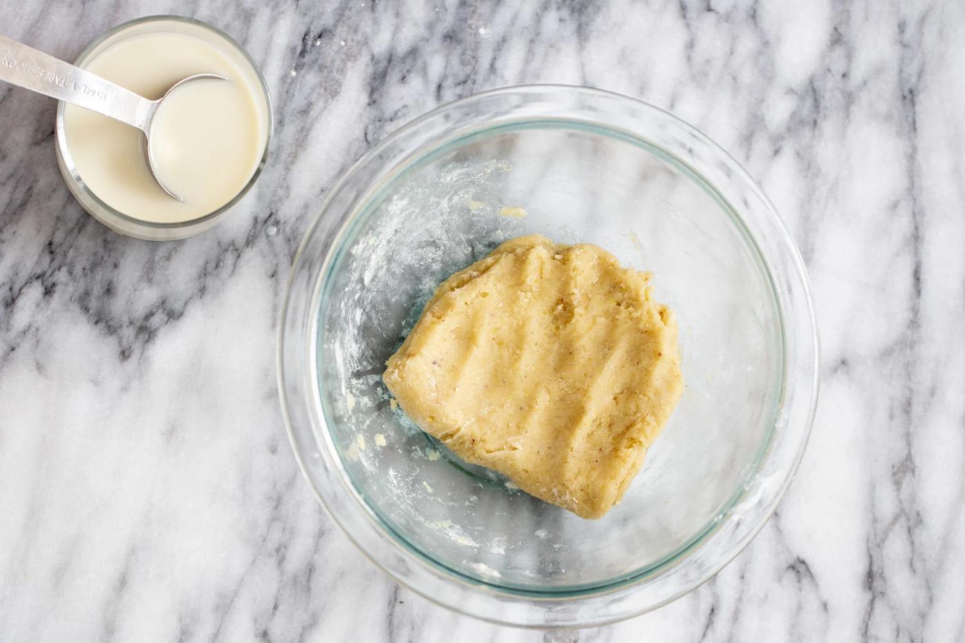 picture demonstrating how to knead vegan gulab jamun batter in a glass bowl