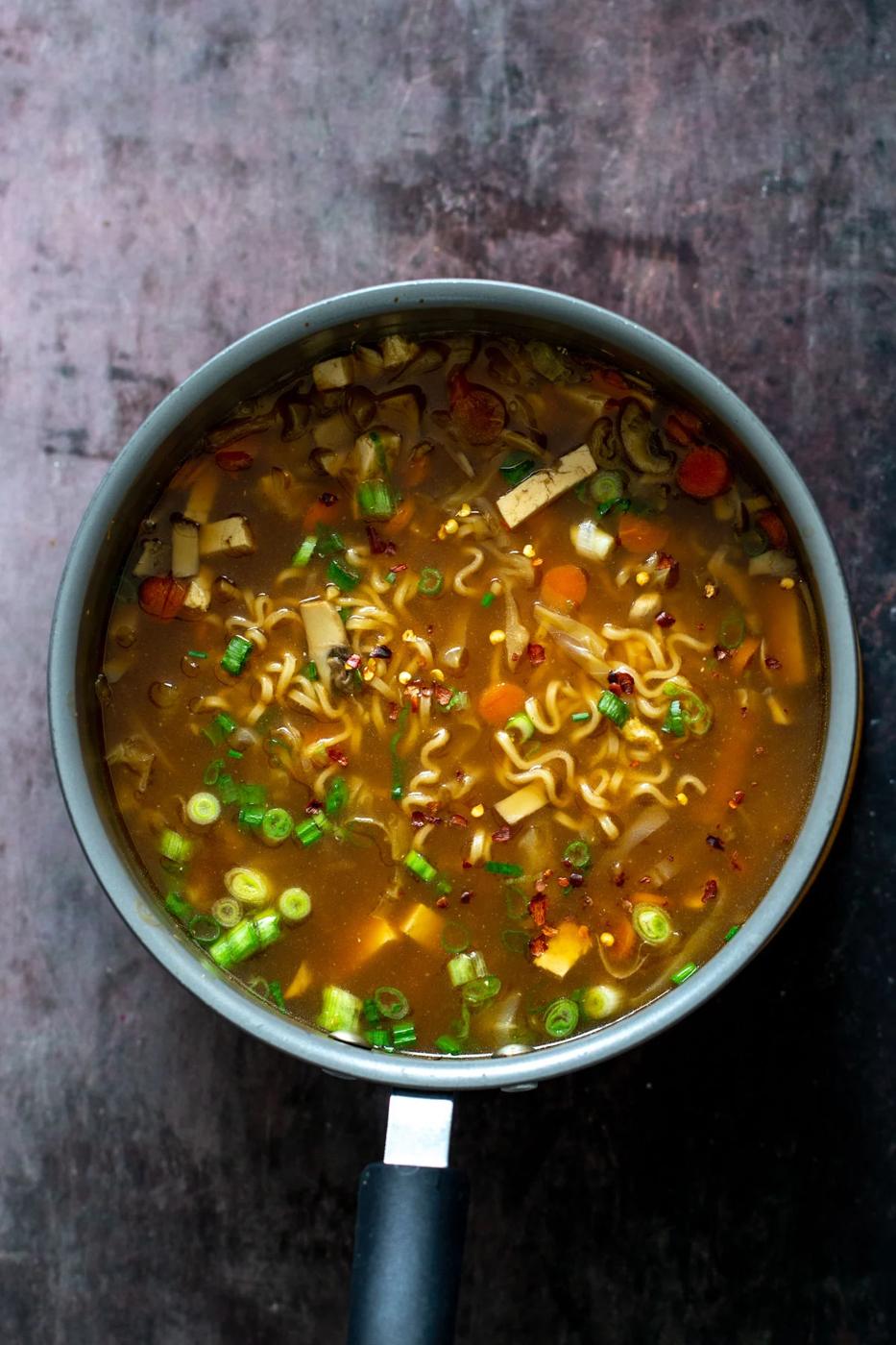 overhead shot of a pot of vegan hot and sour soup with ramen noodles and mushrooms