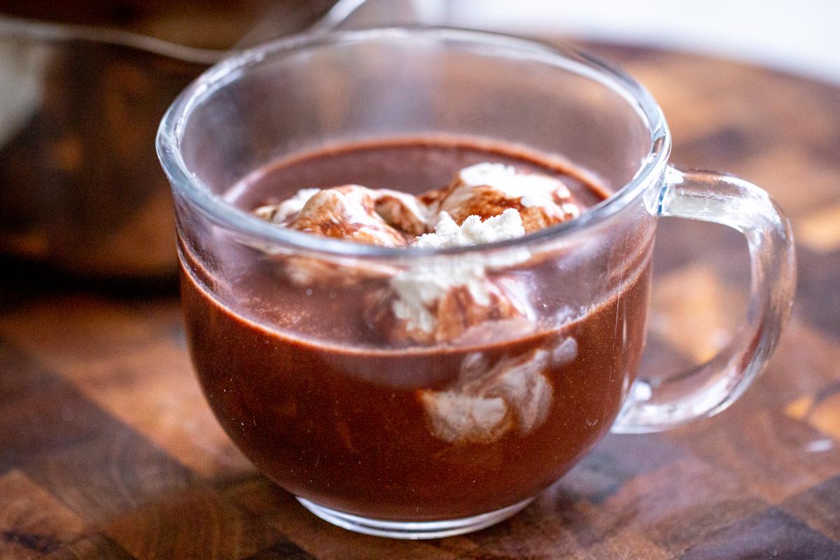 a glass with vegan hot chocolate topped with coconut cream
