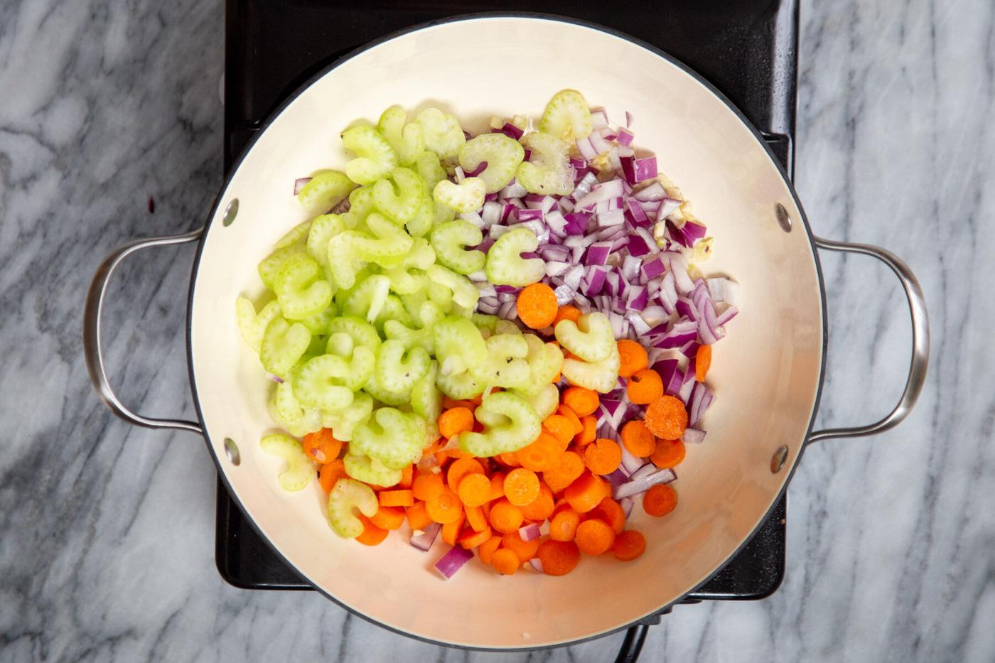 celery, carrots and onions in a sauteeing pan