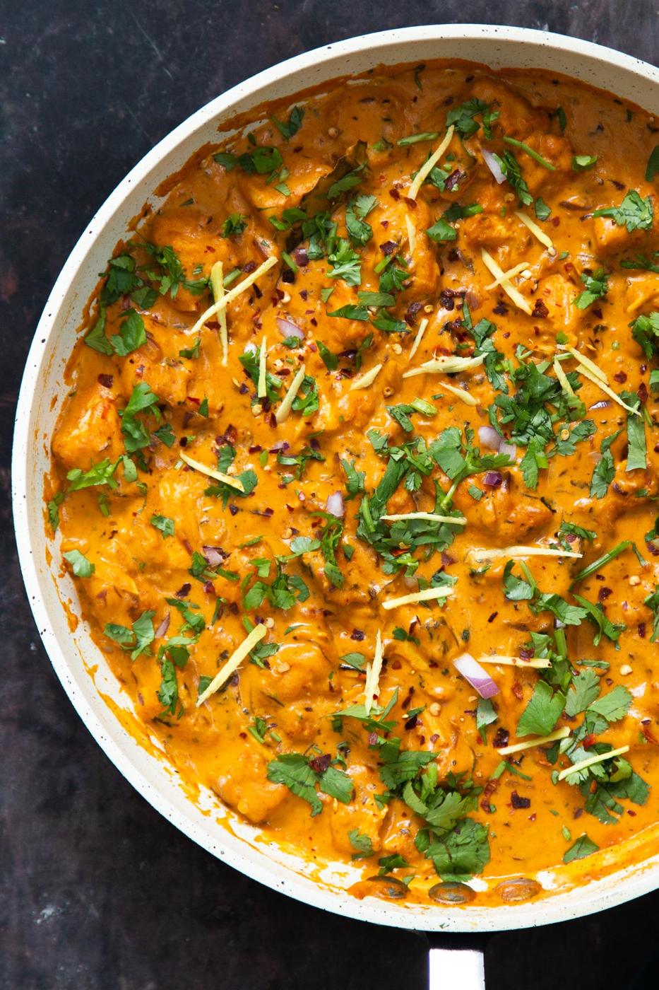 a pan with creamy vegan lasooni tofu curry sprinkled with ginger and fresh chopped cilantro