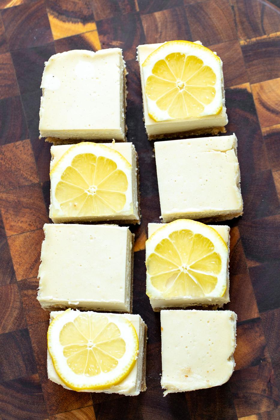 vegan lemon bars on a wooden chopping board topped with lemon slices
