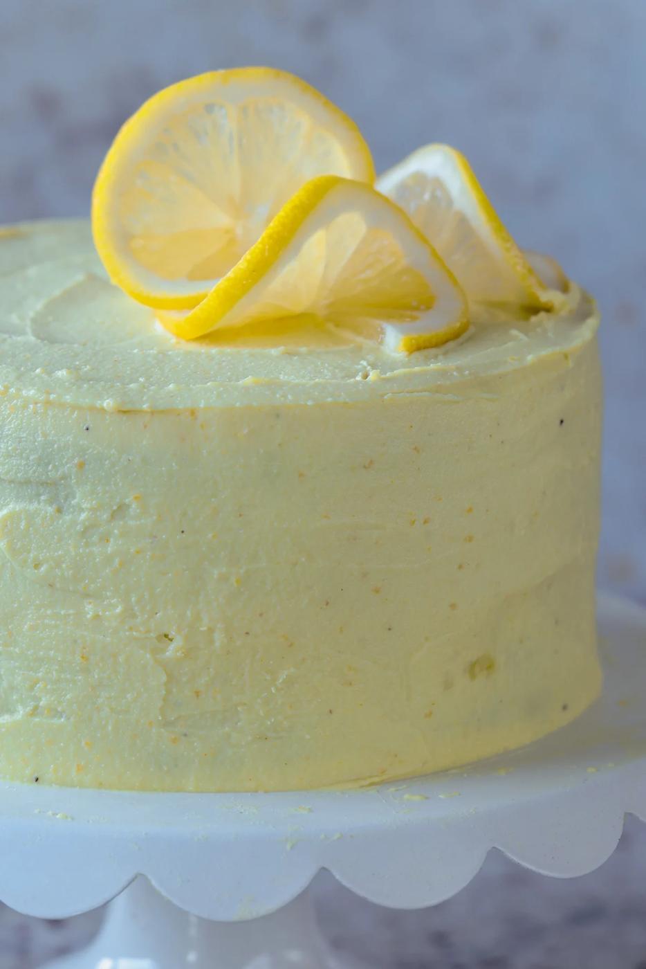 close-up of vegan lemon cake on the serving tray after frosting and topping with lemon slices