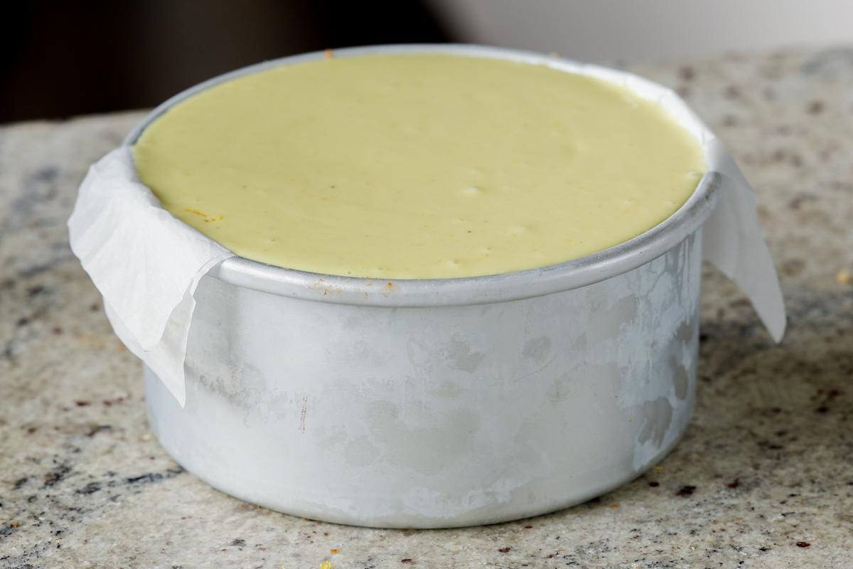 adding the second layer of frosting to the cakes in the pan