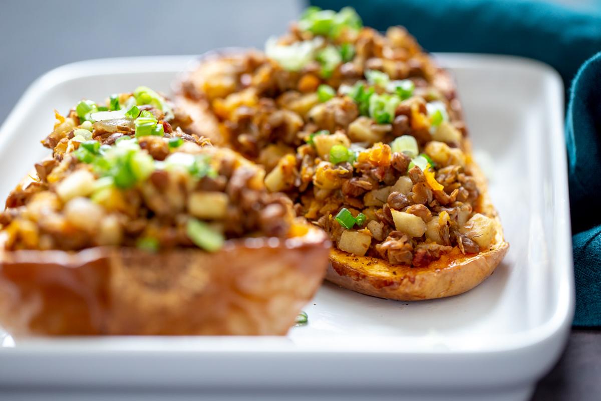 side view of two stuffed butternut squash halves in a casserole dish