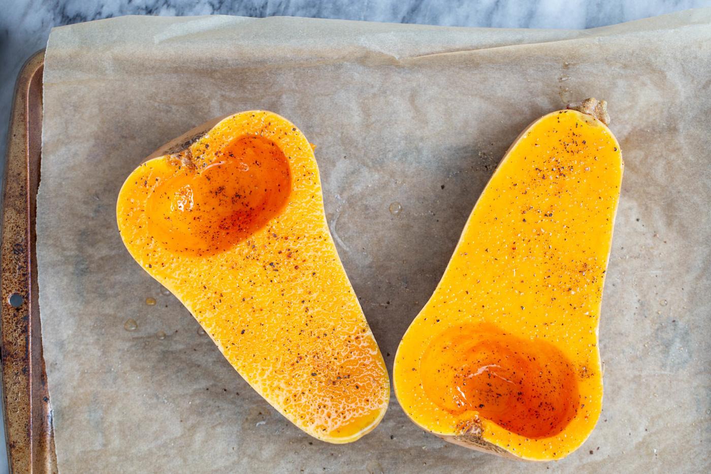 2 butternut squash halves on a baking sheet drizzled with oil and sprinkled with salt and pepper