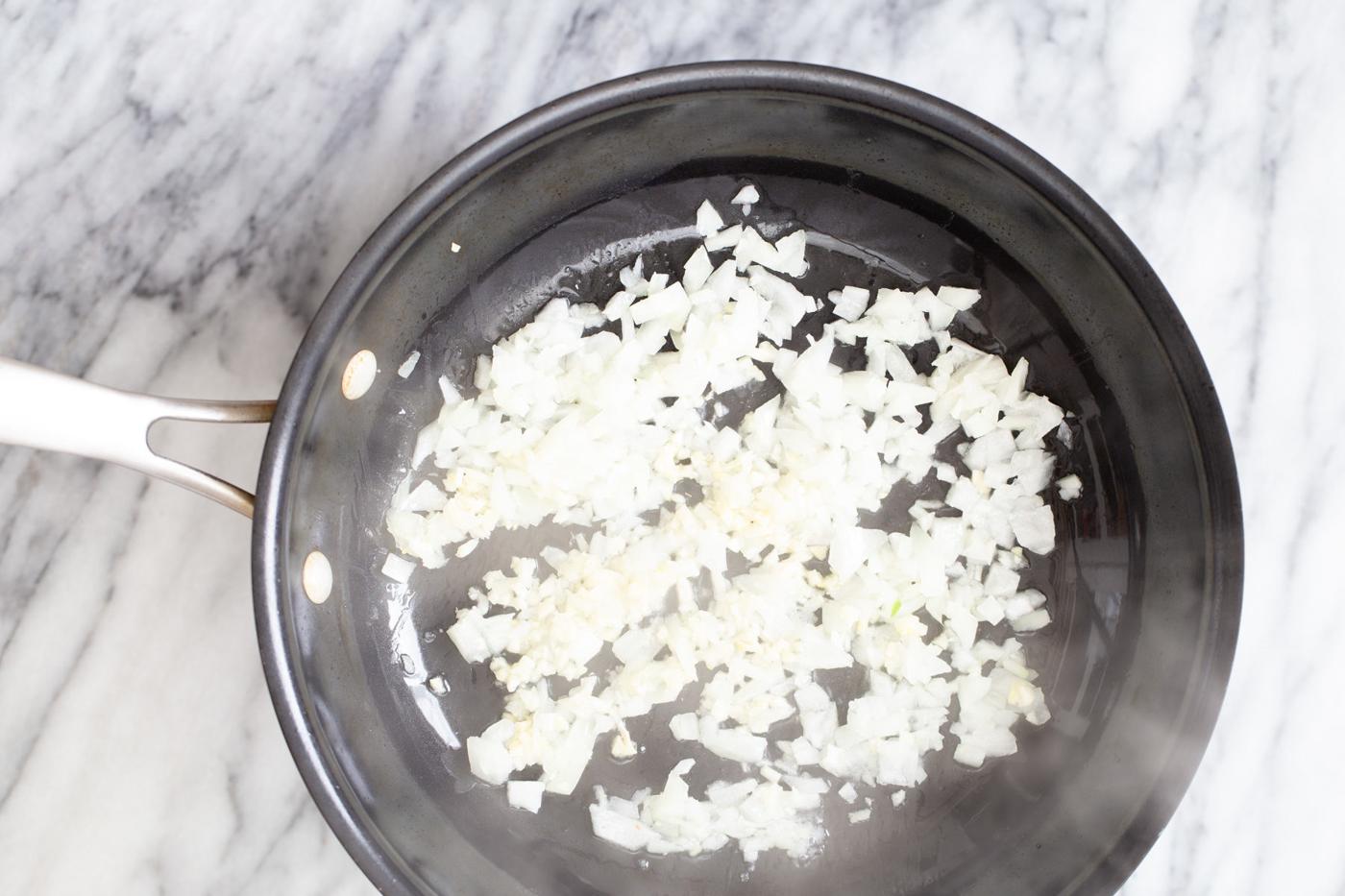 chopped onion being sauteed in a pan