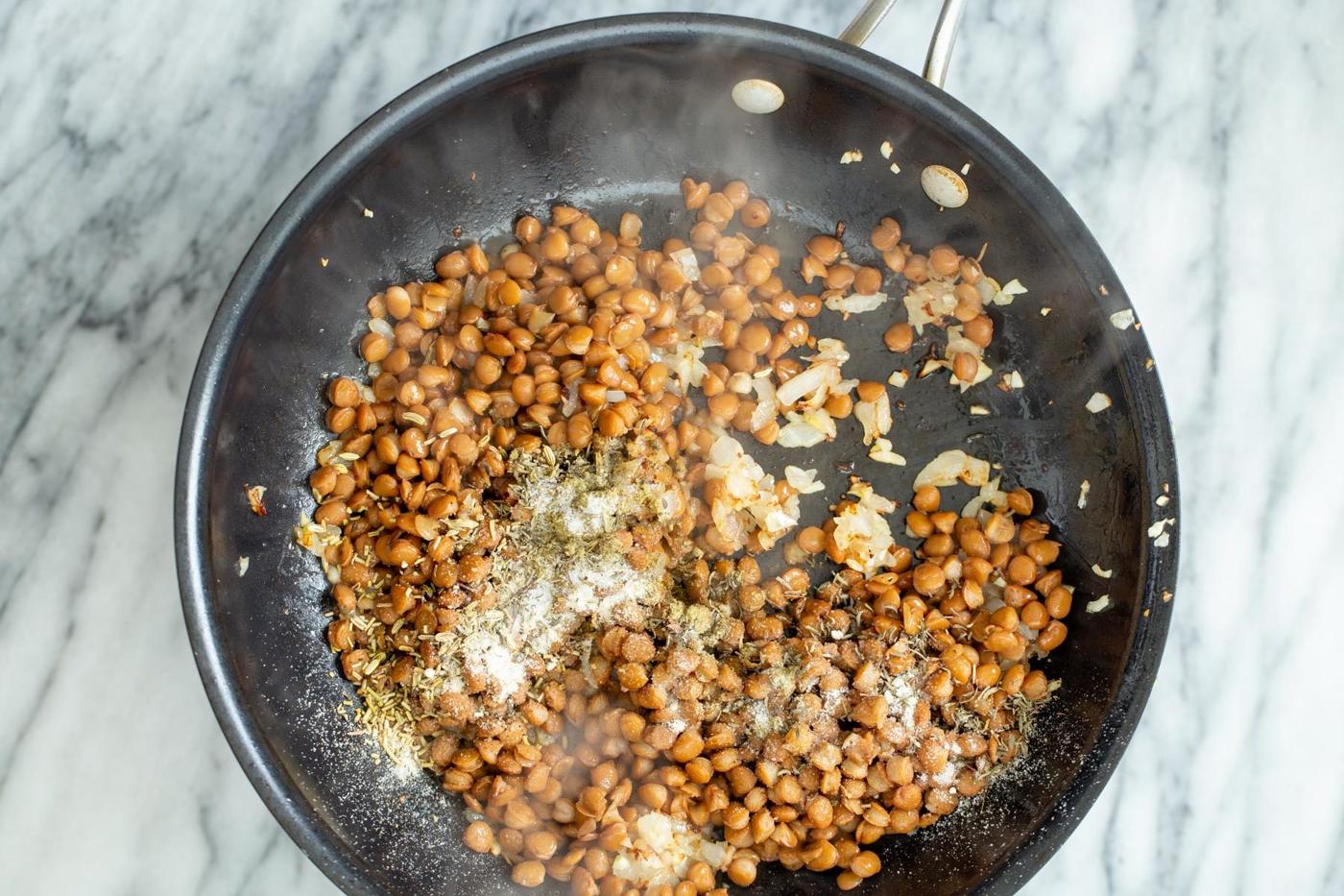 lentil onion stuffing mixture and spices sauteeing in a frying pan