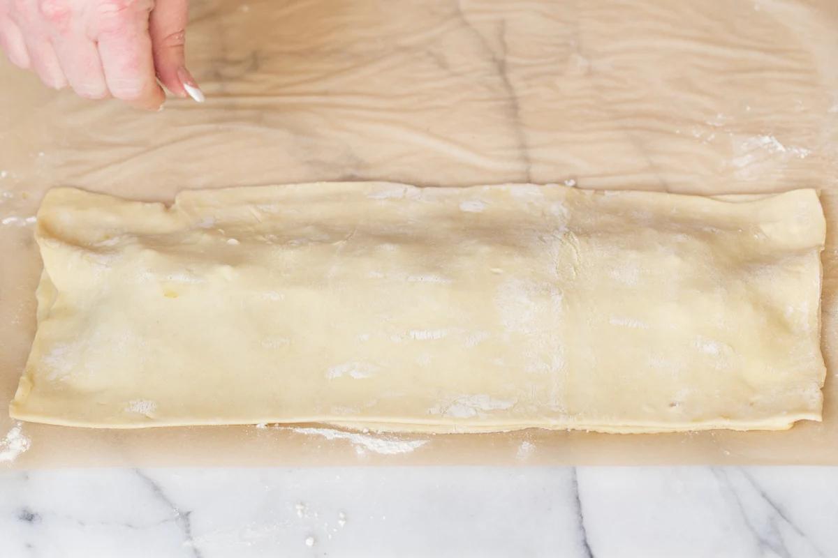 vegan sambusa pie being assembled by wrapping filling in a puff pastry case