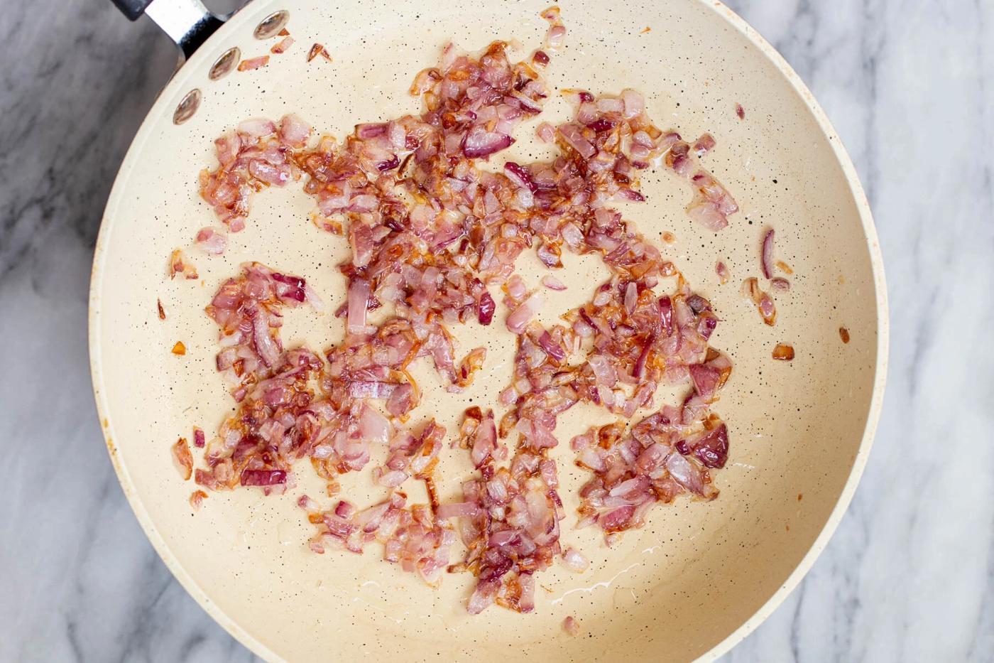 chopped red onions frying in a pan