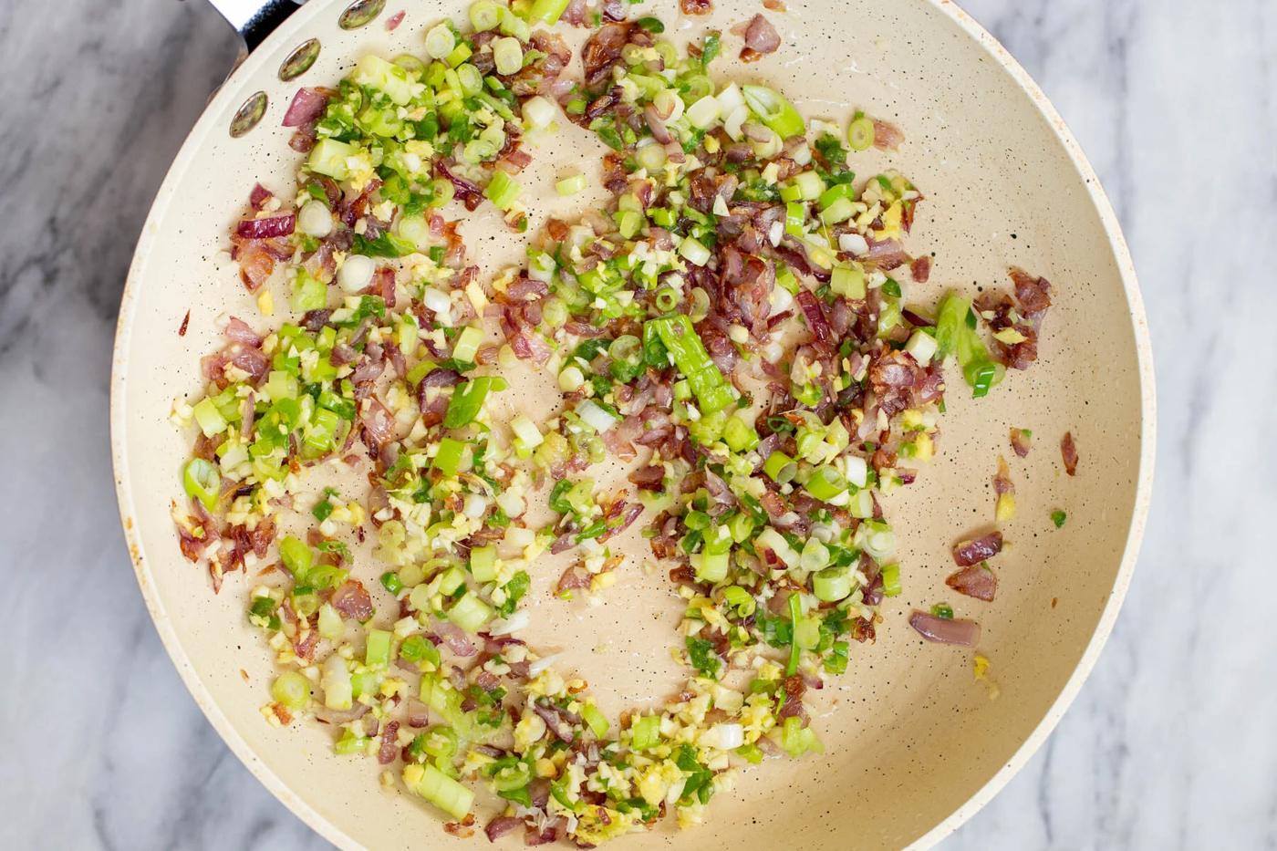 chopped green onion, garlic and ginger in a frying pan