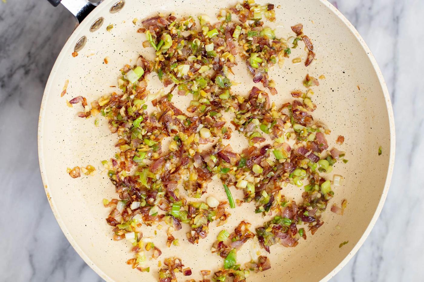 garlic, green chili and onion in a frying pan
