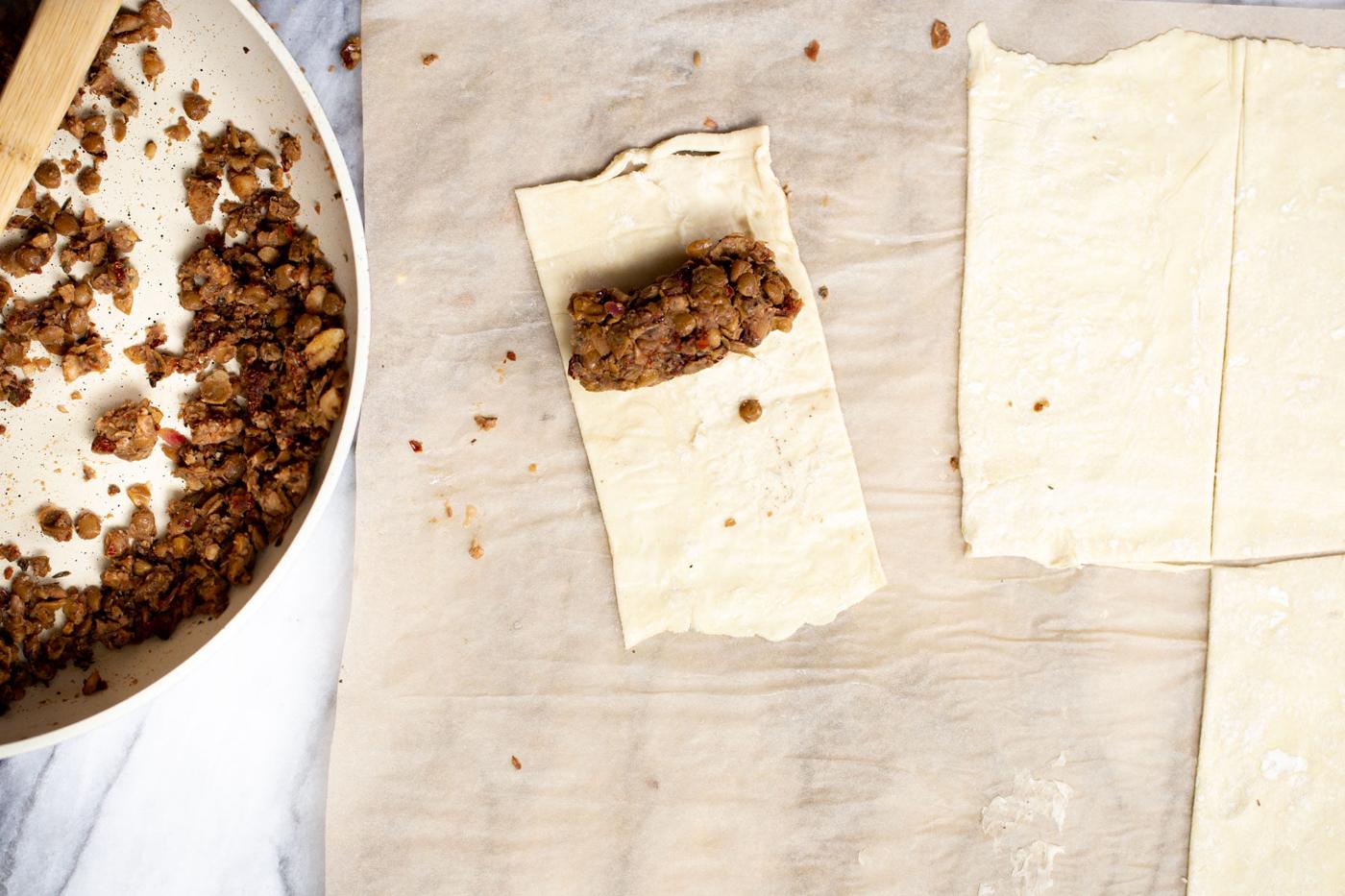 lentils sausage stuffing being scooped on puff pastry