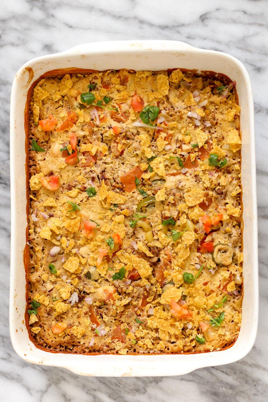a casserole dish with vegan mac and cheese bake topped with crushed tortilla chips