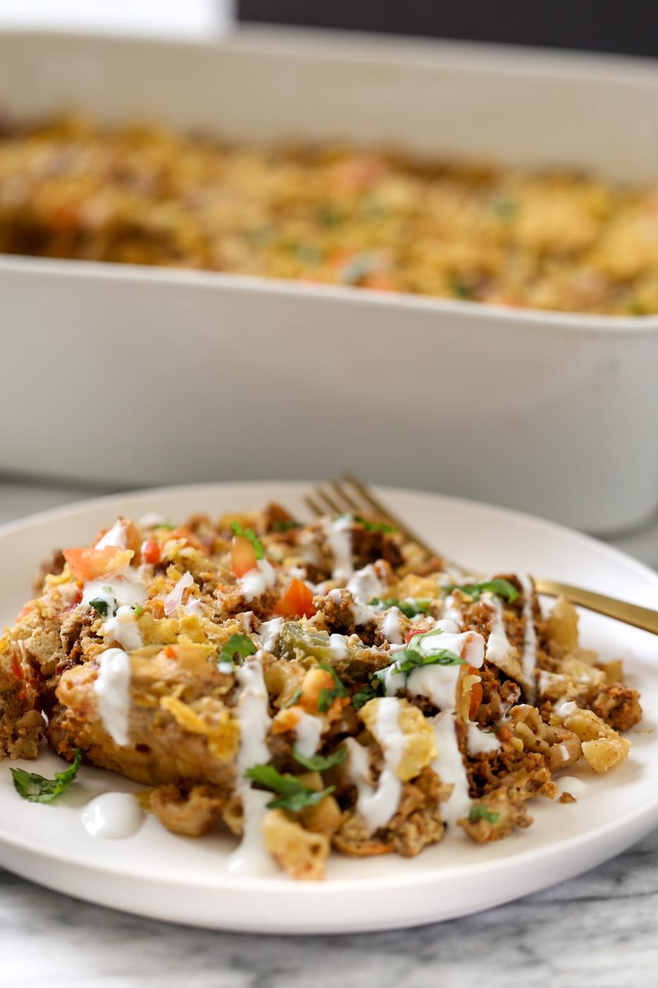 a serving of vegan mac and cheese taco bake drizzled with vegan sour cream