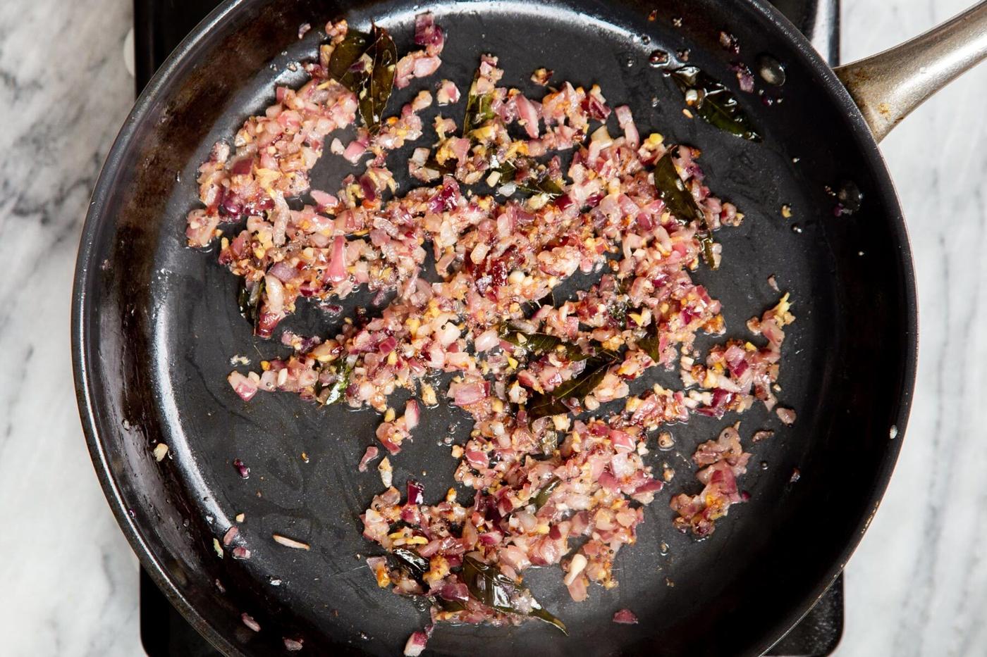 fried onion and ginger with tempering in a frying pan