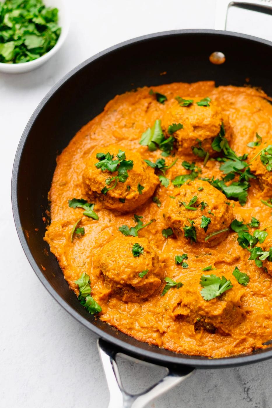 side view of a skillet with vegan malai kofta sprinkled with cilantro