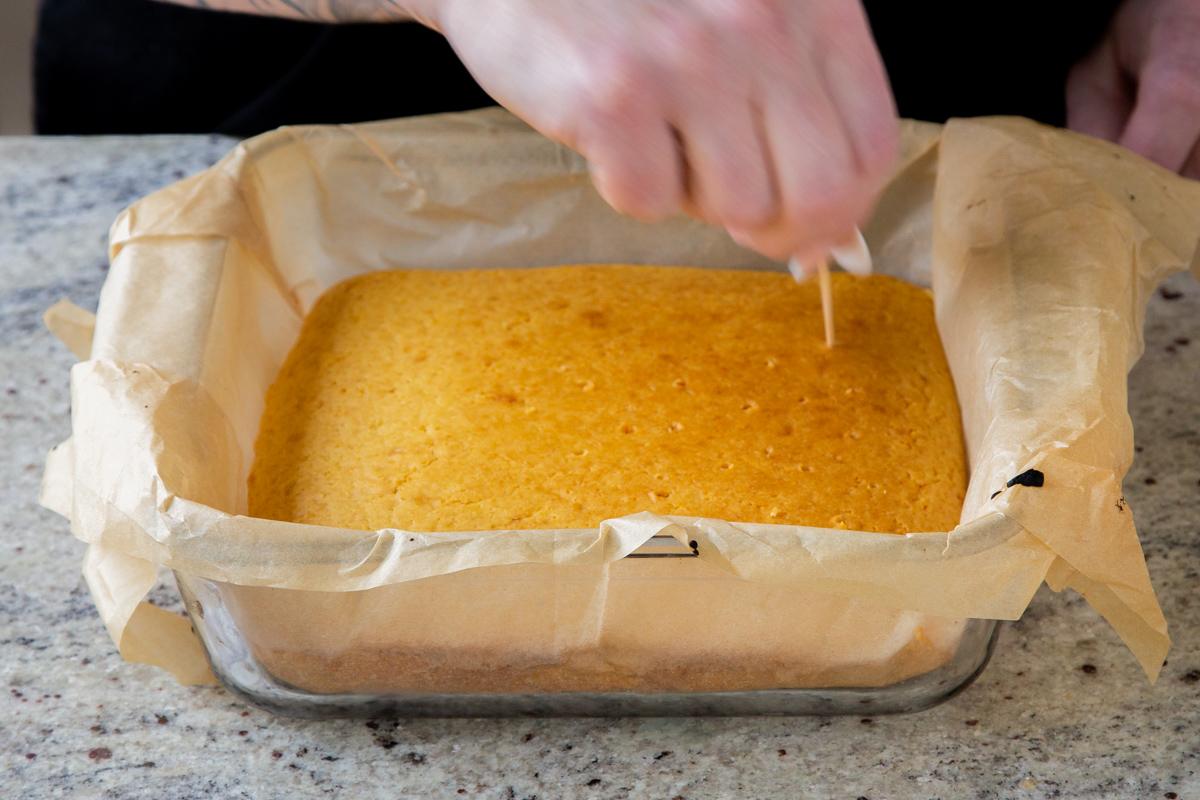 poking holes into mango tiramisu cake layer