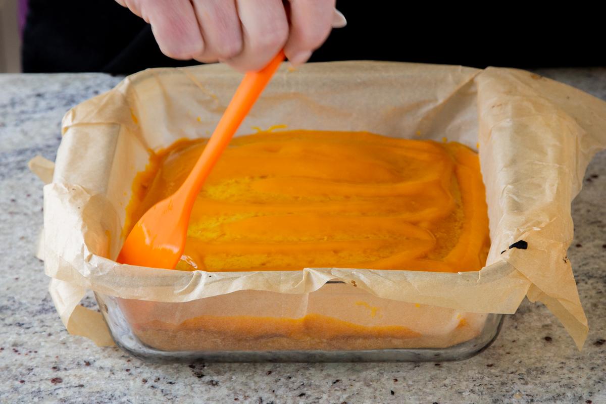 spreading mango puree onto mango tiramisu cake layer