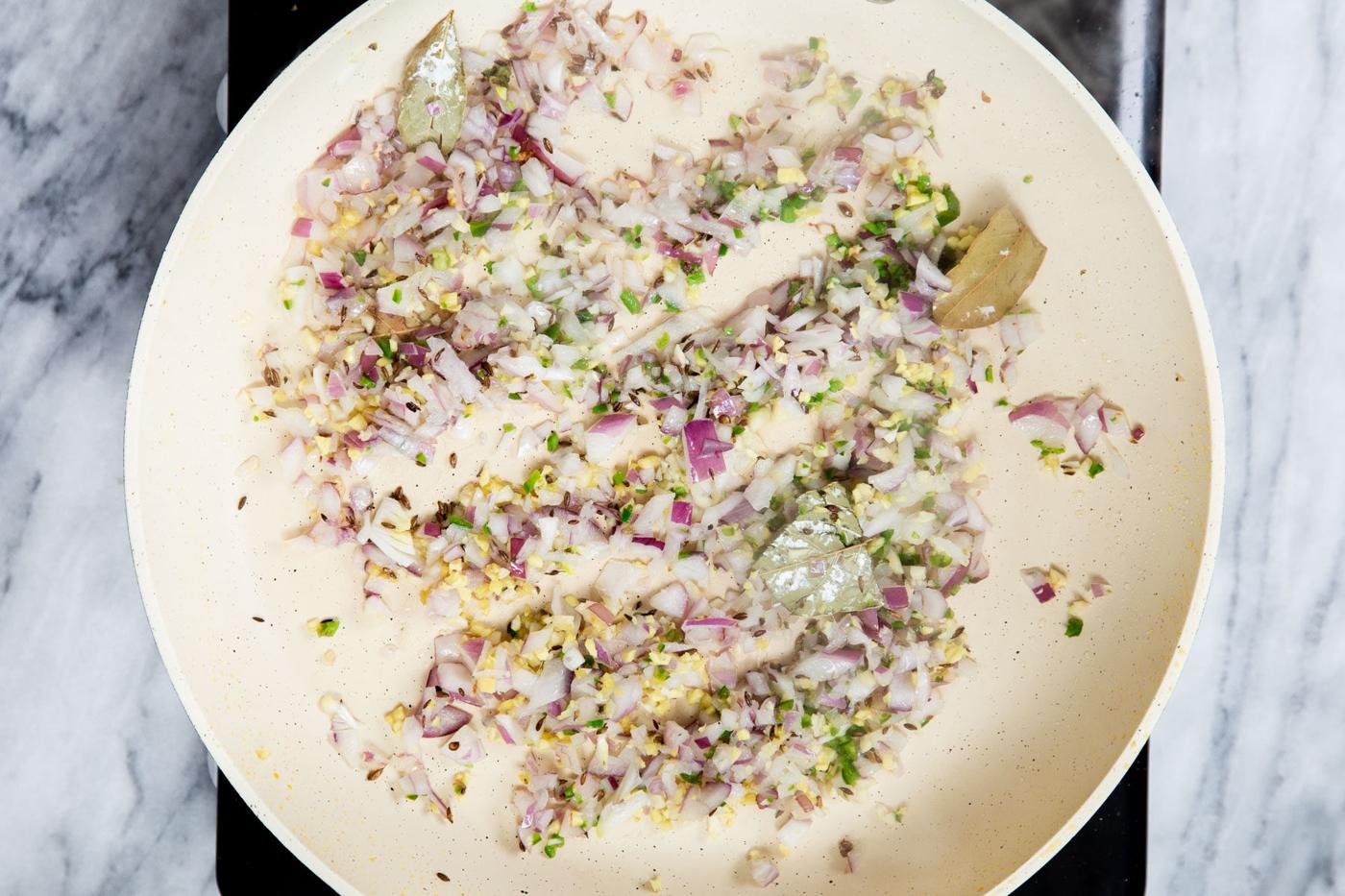 diced onions and ginger sauteeing in a pan with spices