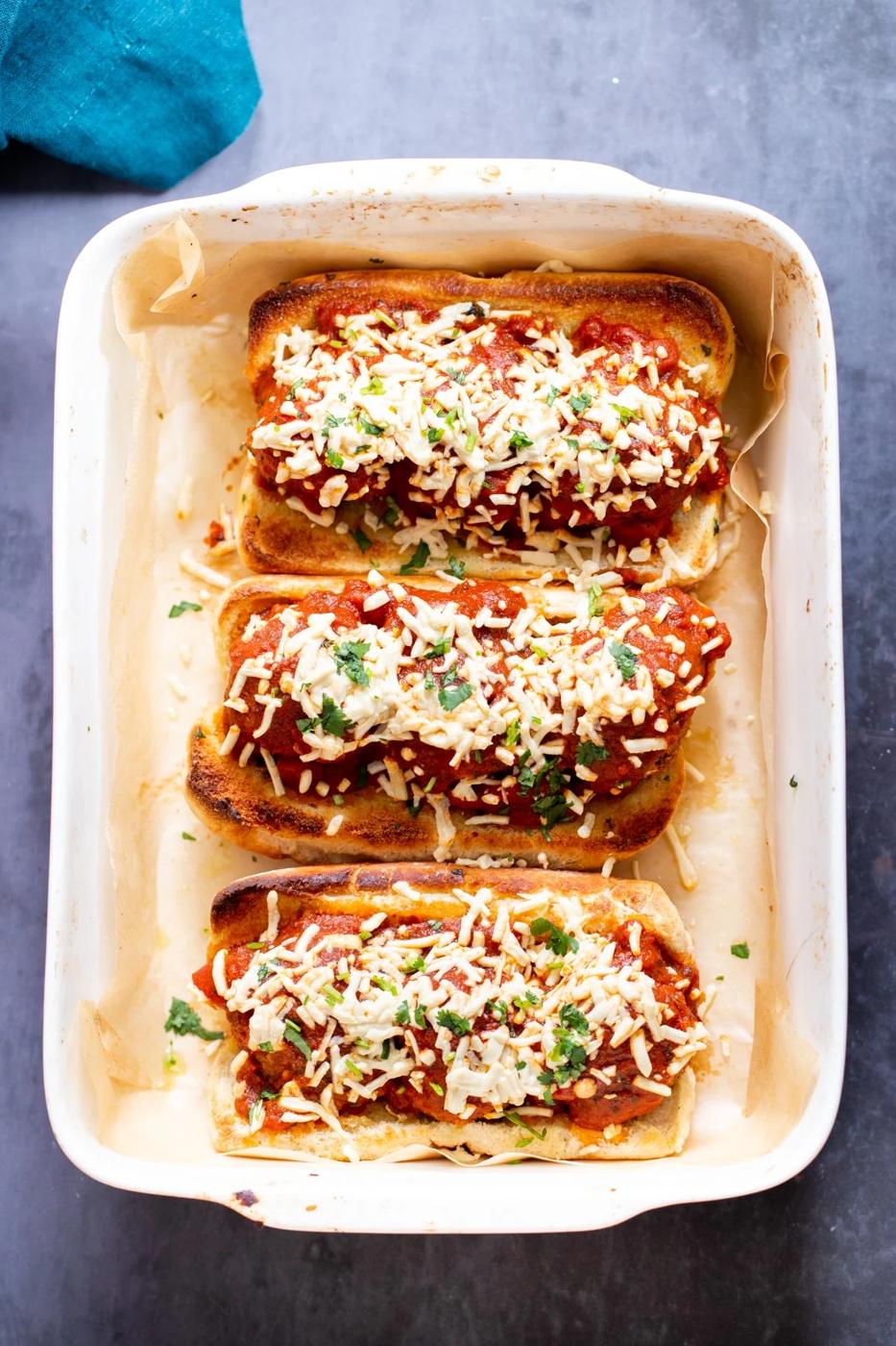 vegan meatball subs topped with lentil meatballs and sprinkled with vegan cheese shreds
