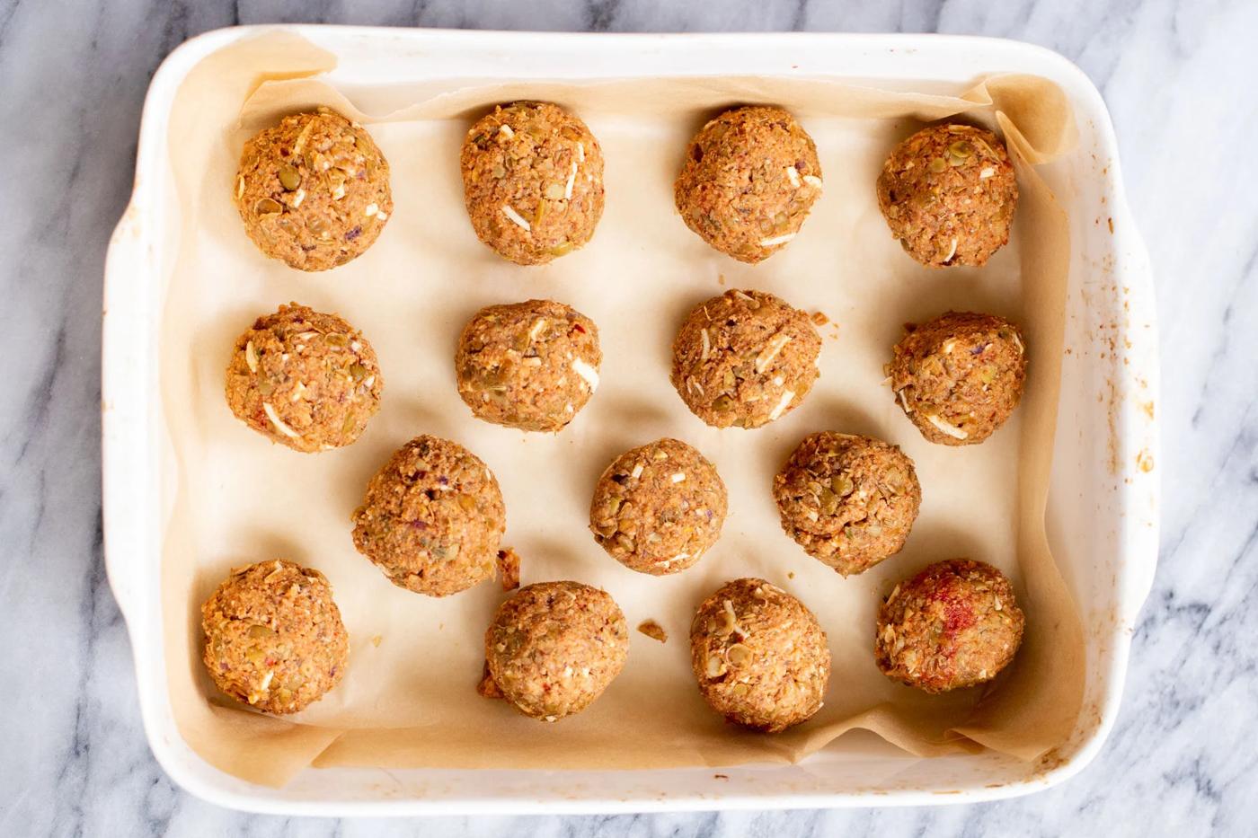 vegan lentil meatballs with cheese shreds in a white casserole dish