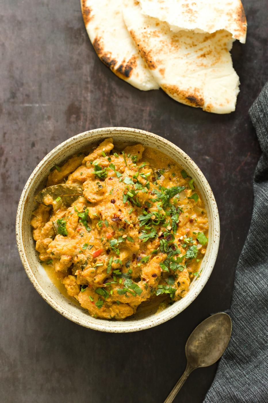 overhead shot of a bowl of vegan methi chicken with some naan bread on the side