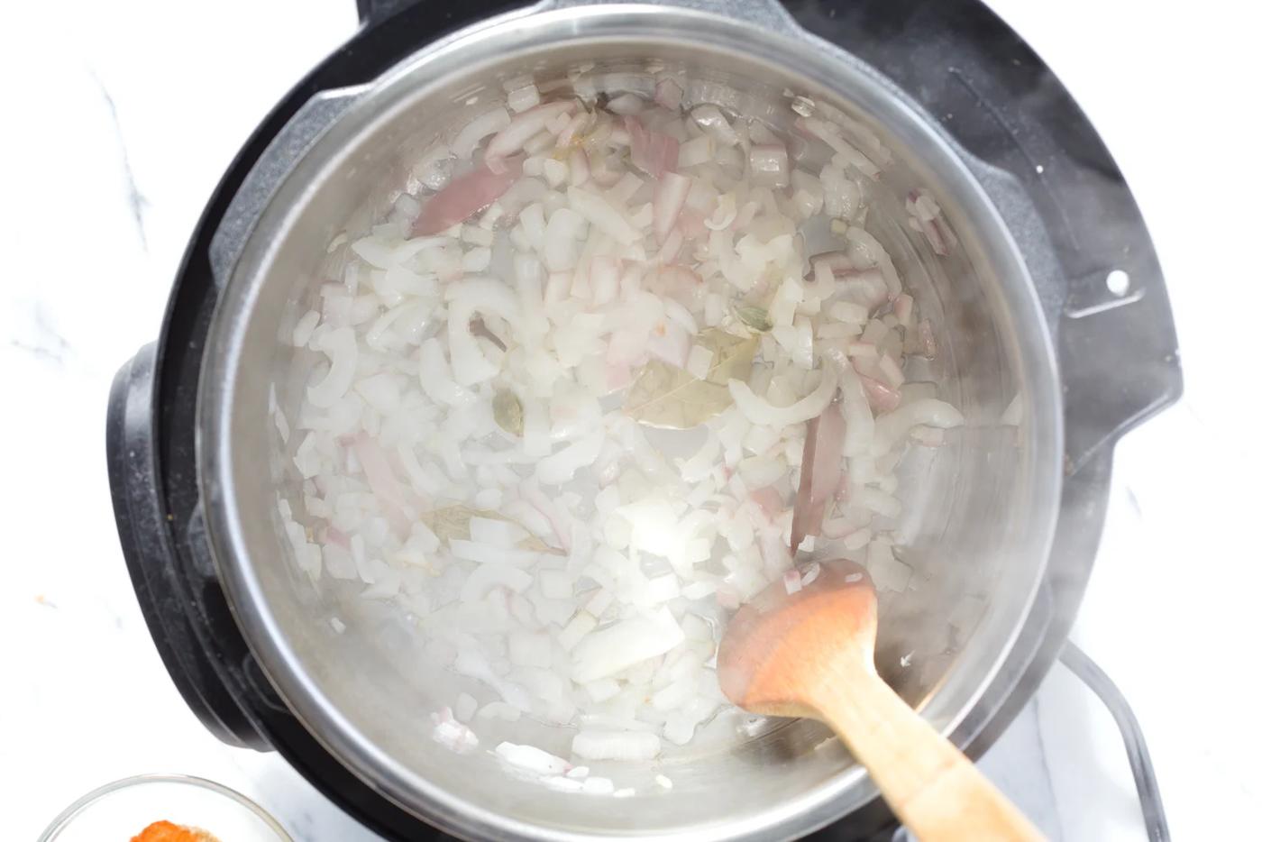 minced onions being sauteed in an instant pot to make vegan curry recipe