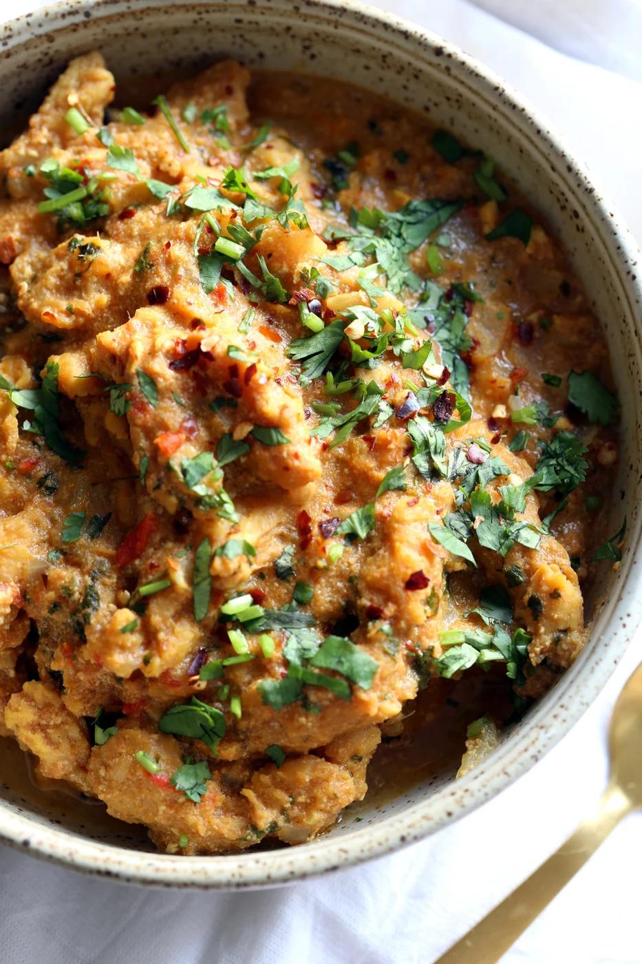 overhead shot of a bowl of vegan fenugreek chicken curry topped with chopped cilantro
