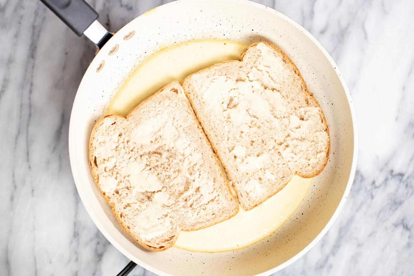 fried vegan eggs in a sauteeing pan topped with bread slices