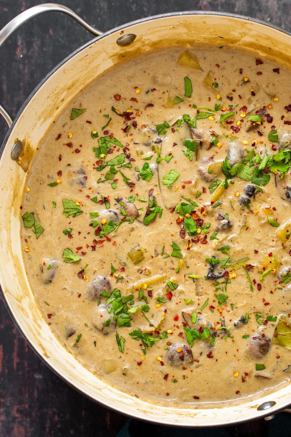 creamy vegan mushroom chowder in a pot sprinkled with fresh herbs