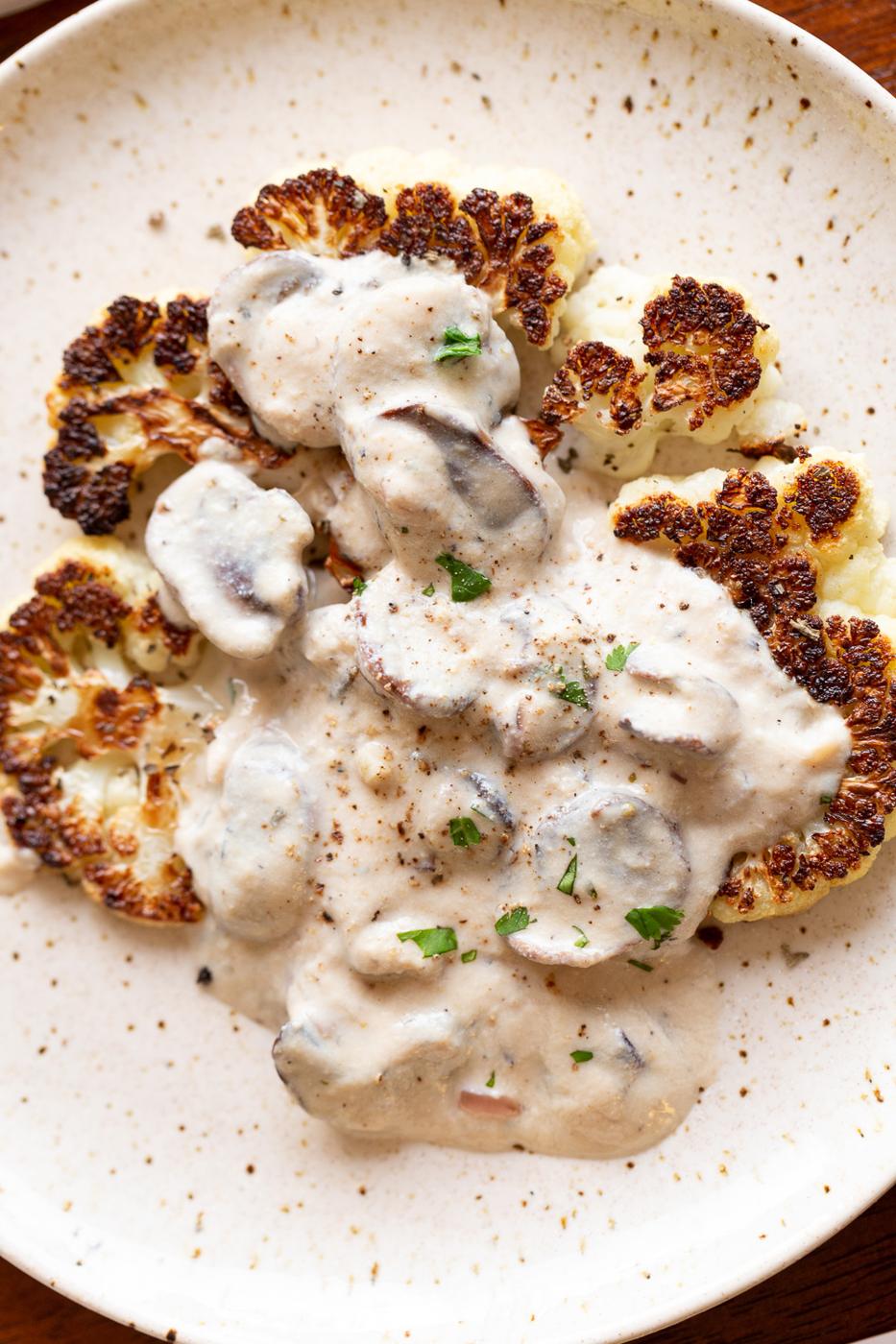 Vegan Mushroom Sauce with Cauliflower Steak on a white plat