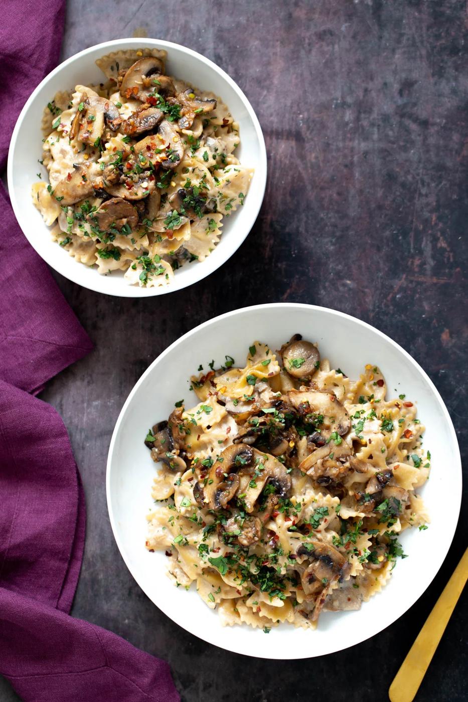 two plates with farfalle pasta topped with vegan mushroom stroganoff