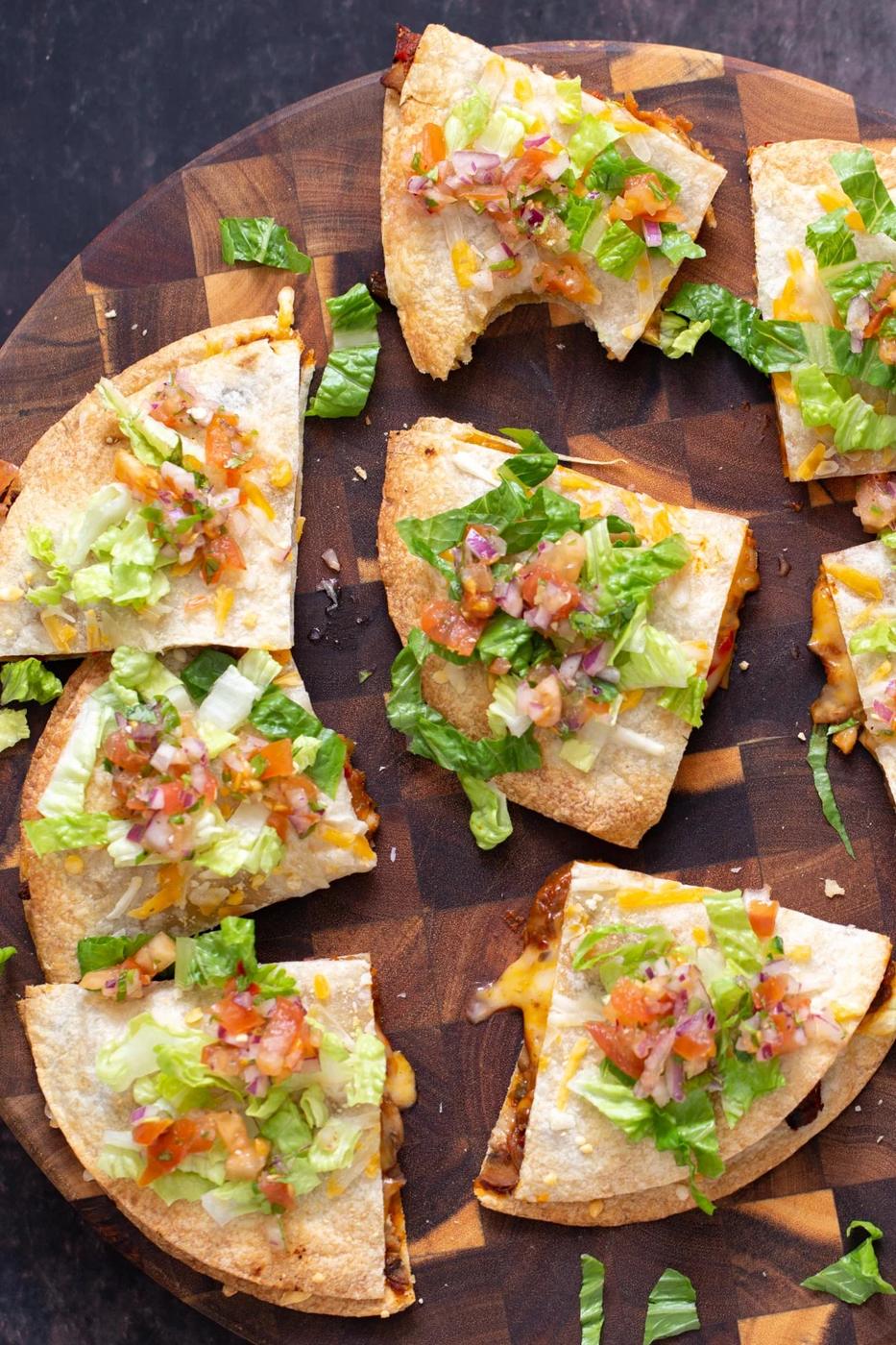 vegan mushroom and bell pepper tostadas cut into wedges and served on a wooden board