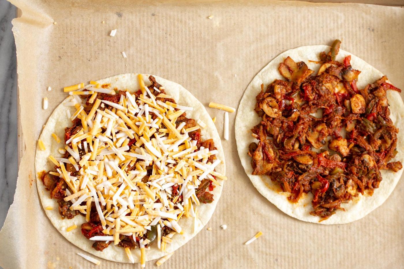 vegan tostadas topped with vegetable filling and cheese placed on a sheet pan