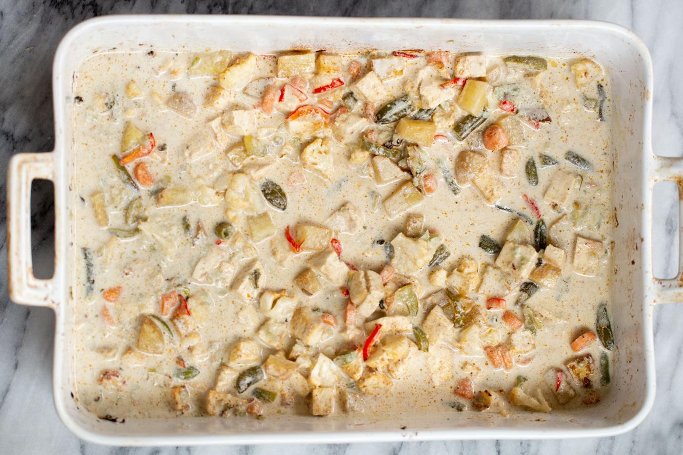 creamy cashew sauce being poured on top of roasted veggies