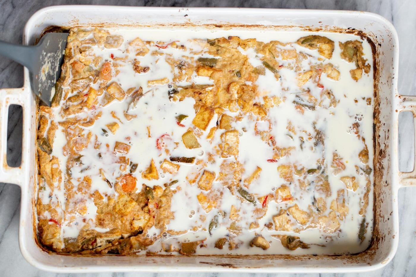 milk being added to tofu and veggies in a white casserole dish