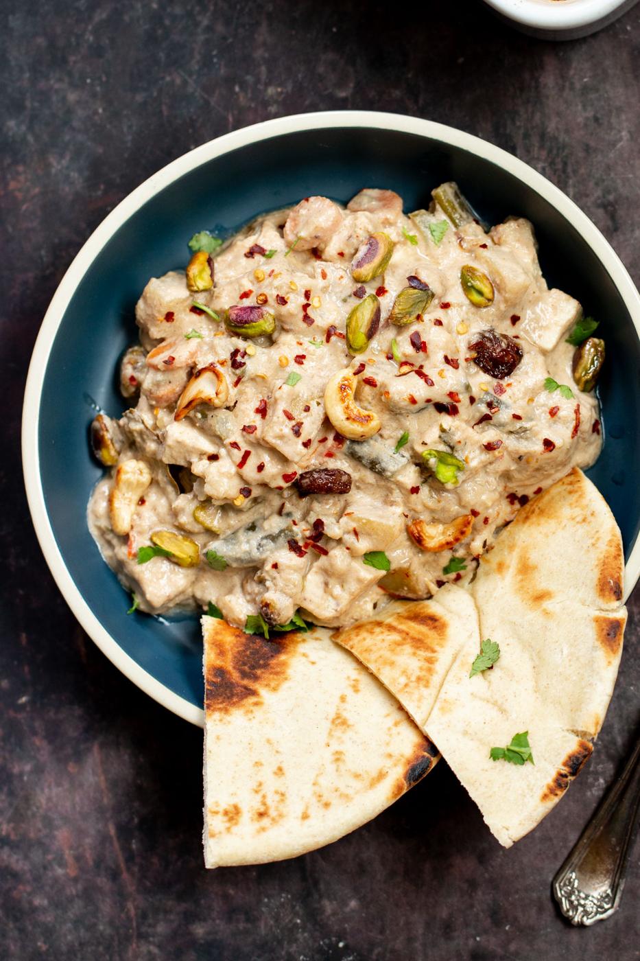 a bowl of Baked Vegan Navratan Korma topped with chopped nuts and red chili flakes