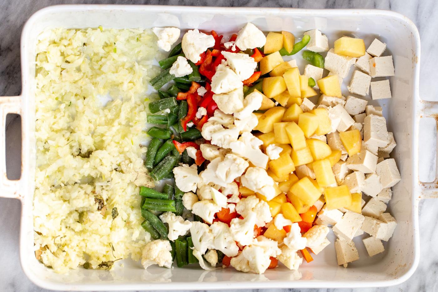 tofu cubes, veggies and minced ginger and garlic in a white casserole dish