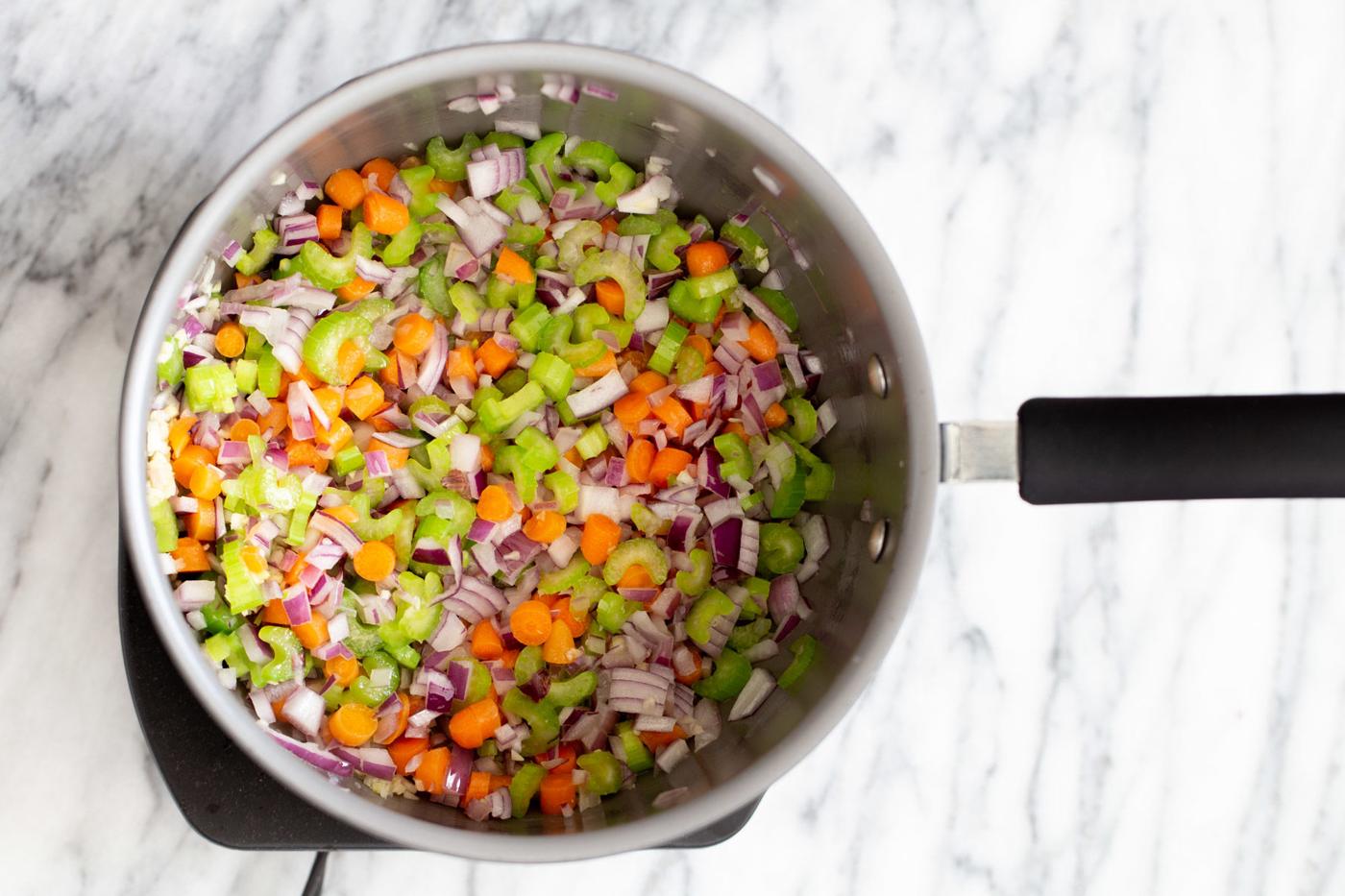 celery carrots and onions sauteeing in a saucepan