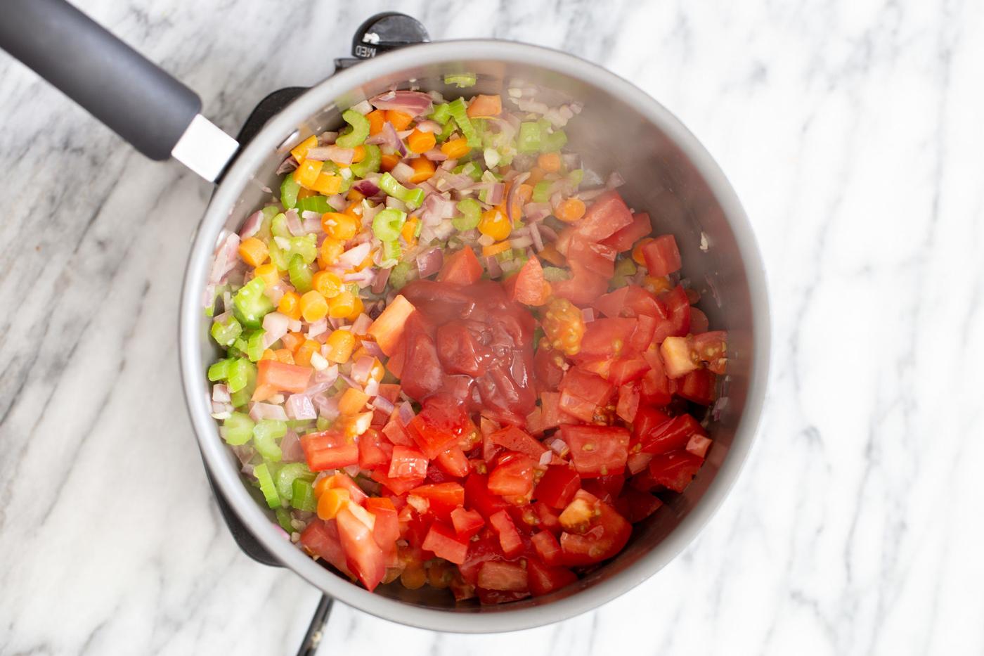 overhead shot of a pot with sauteed veggies with tomato paste and diced tomatoes