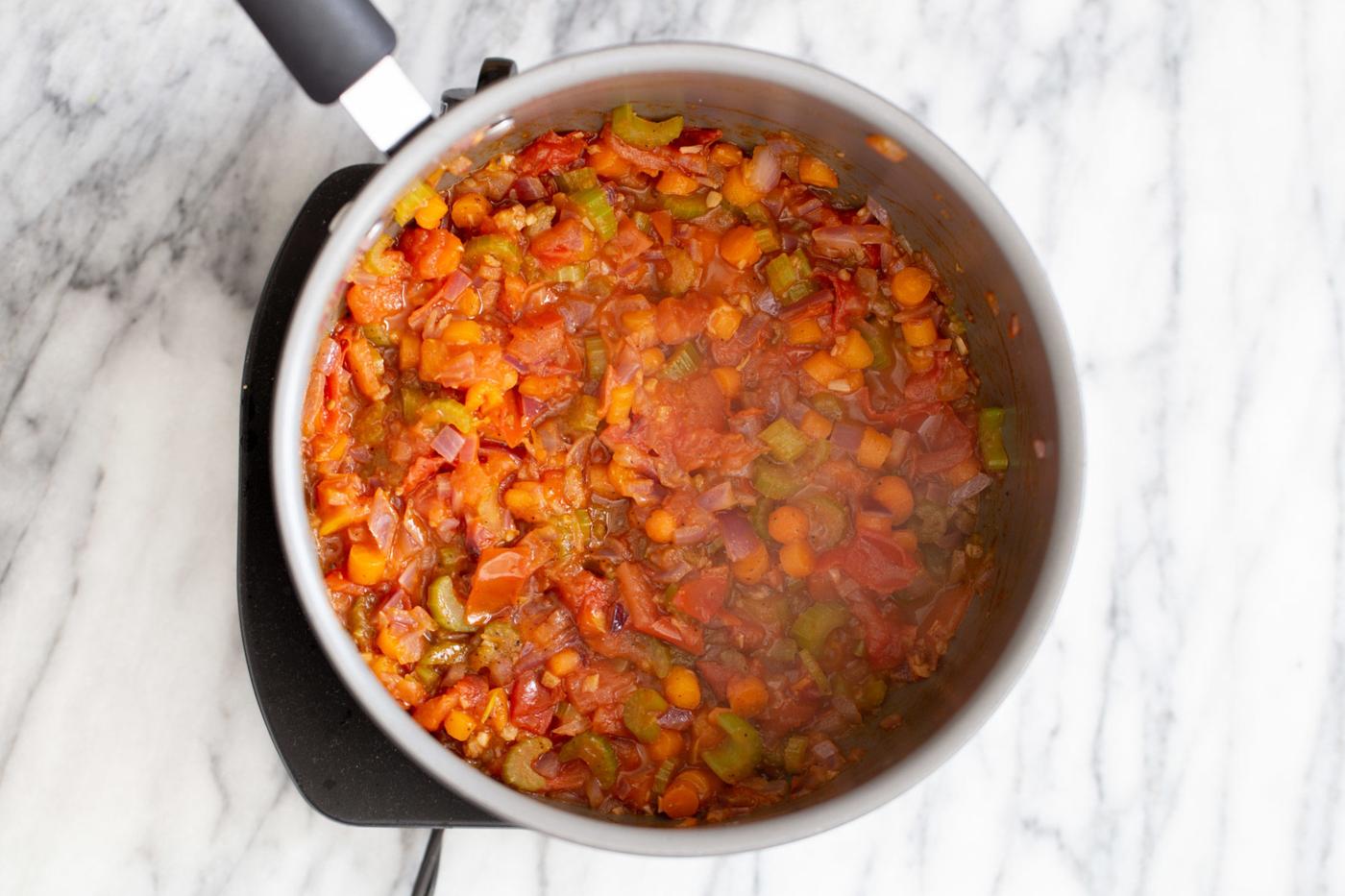 chopped veggies cooking in tomato broth to make vegan pasta e fagioli