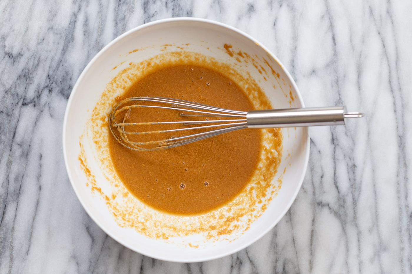 ingredients being mixed in a white bowl to make peanut butter thumbprint cookies